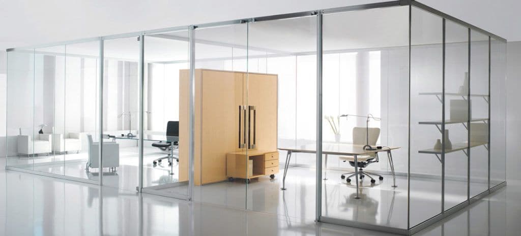 Modern office space featuring glass partitions, showcasing custom glass design and tempered glass applications, ideal for shower doors, table tops, and mirrors with a sleek, beveled glass edge.