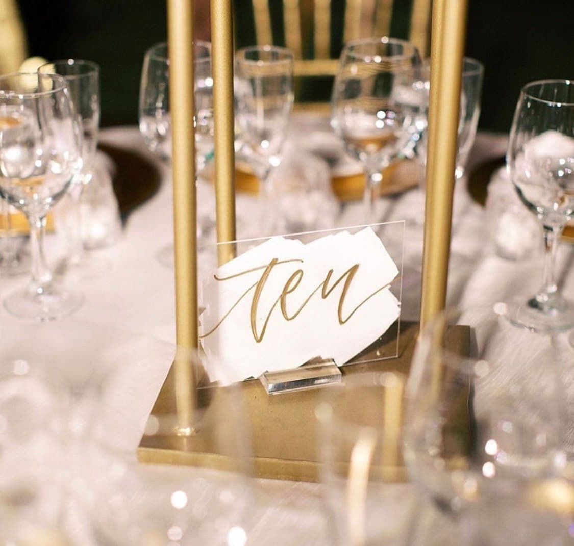 Elegant table setting featuring a glass table number display among wine glasses