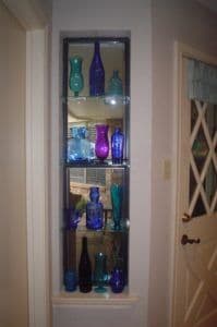 Custom glass display featuring blue and purple bottles on tempered glass shelves