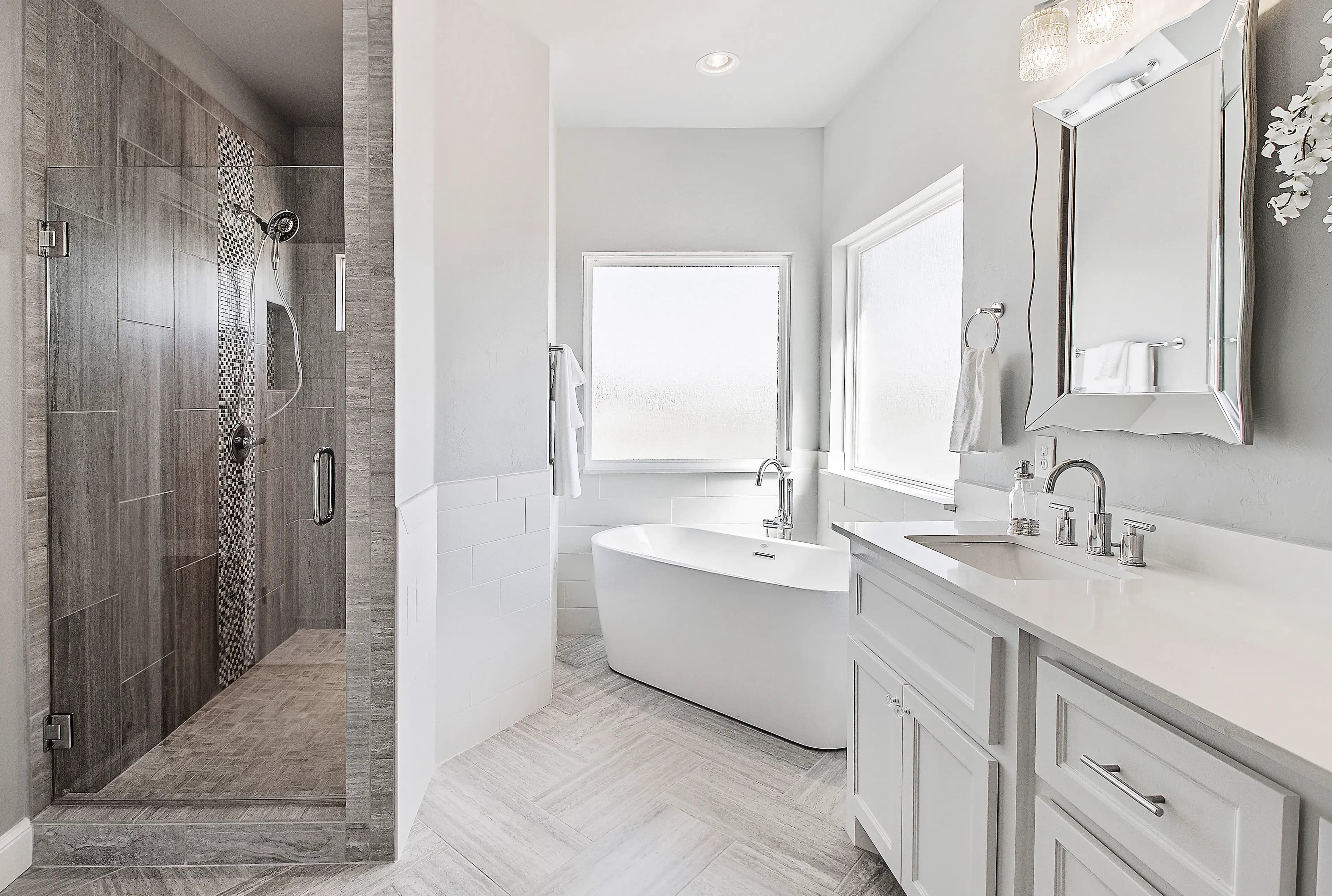 Stylish bathroom featuring custom shower doors, a modern freestanding bathtub, a sleek mirror, and elegant countertops, highlighting high-quality tempered and beveled glass finishes.