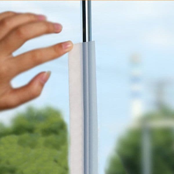 Hand removing protective film from a custom glass shower door, showcasing modern design and beautiful tempered glass finish.