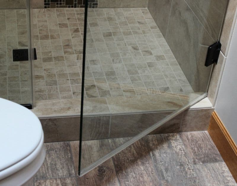 Custom glass shower door installation with a clear tempered glass panel