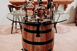 Custom glass tabletop on a wooden barrel with bottles