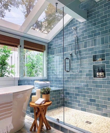 Custom glass shower doors in a modern bathroom featuring a blue tiled shower