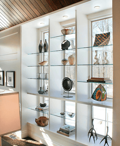 Shelving system built into wall in front of windows adorned in white