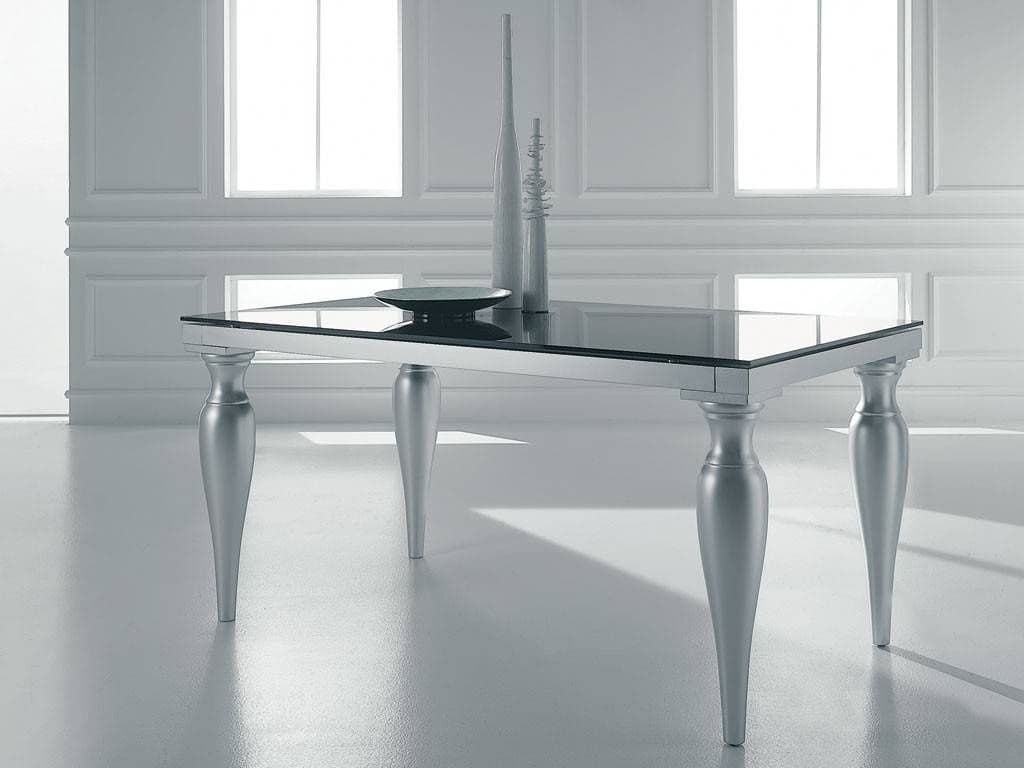 Contemporary glass table with a sleek beveled edge, featuring silver legs, set in a bright room, showcasing custom glass design ideal for modern interiors.
