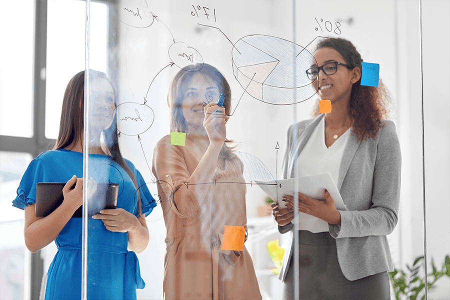 Business meeting brainstorming session with women using a glass partition; highlighting custom glass applications like shower doors and mirrors.
