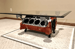 Custom glass coffee table with a tempered glass top resting on a repurposed engine block base