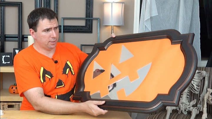 Man holding a custom mirror with a pumpkin design
