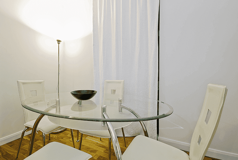 Modern dining area featuring a round glass table with a beveled edge