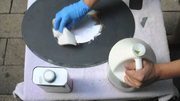 A person wearing blue gloves is cleaning a circular