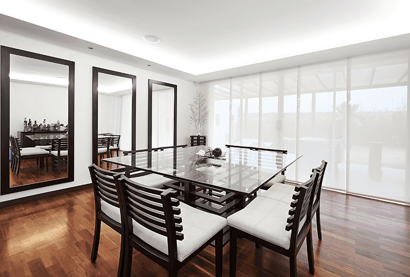 Modern dining room featuring a glass table top and elegant mirrors
