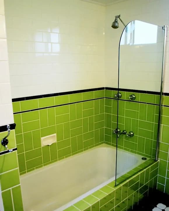Custom glass shower door in a green tiled bathroom featuring tempered glass with a sleek