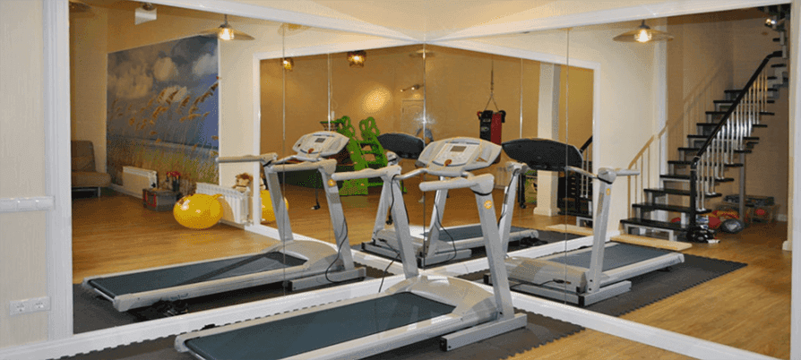 Modern gym interior featuring multiple treadmills and expansive custom mirrors