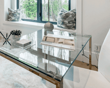 Modern glass table top in a stylish office setting, showcasing custom glass design with a clear finish, complemented by a soft rug and contemporary decor.
