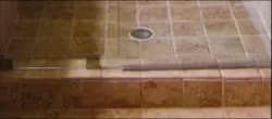 Shower door installation featuring custom glass, showcasing a seamless transition to tiled flooring, emphasizing quality and design.
