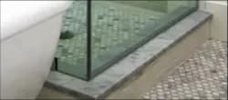 custom glass shower door with beveled glass edge alongside a modern bathtub on a stone base