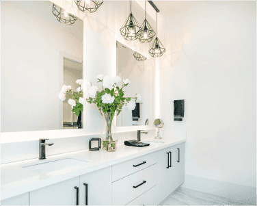 Modern bathroom featuring custom glass mirrors, elegant lighting, and a sleek vanity with floral decor, highlighting the beauty of tempered glass and beveled edges in a stylish setting.