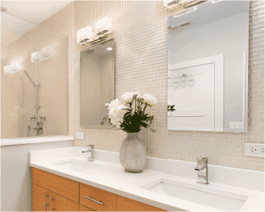 Luxury bathroom featuring custom mirrors, a sleek vanity with a white countertop, and a modern shower with glass doors, highlighting custom glass solutions.