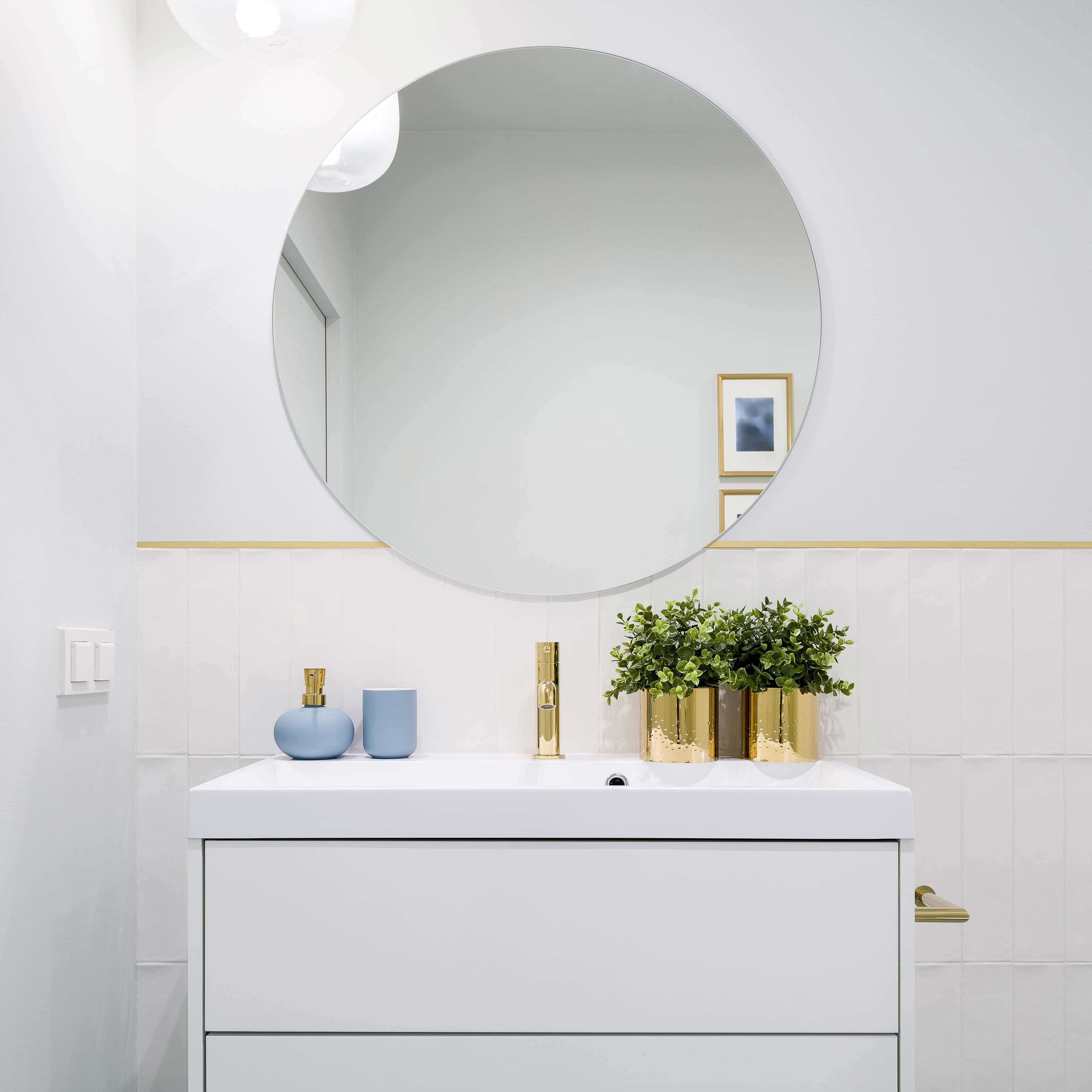 Modern bathroom featuring a circular mirror, stylish sink vanity, and decorative elements, showcasing custom glass designs and elegant finishes.