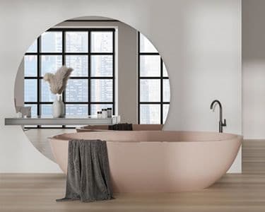 Modern bathroom featuring a pink bathtub, a large circular mirror, and a sleek vanity, showcasing an elegant design with custom glass elements, perfect for shower doors, table tops, and beveled glass edges.