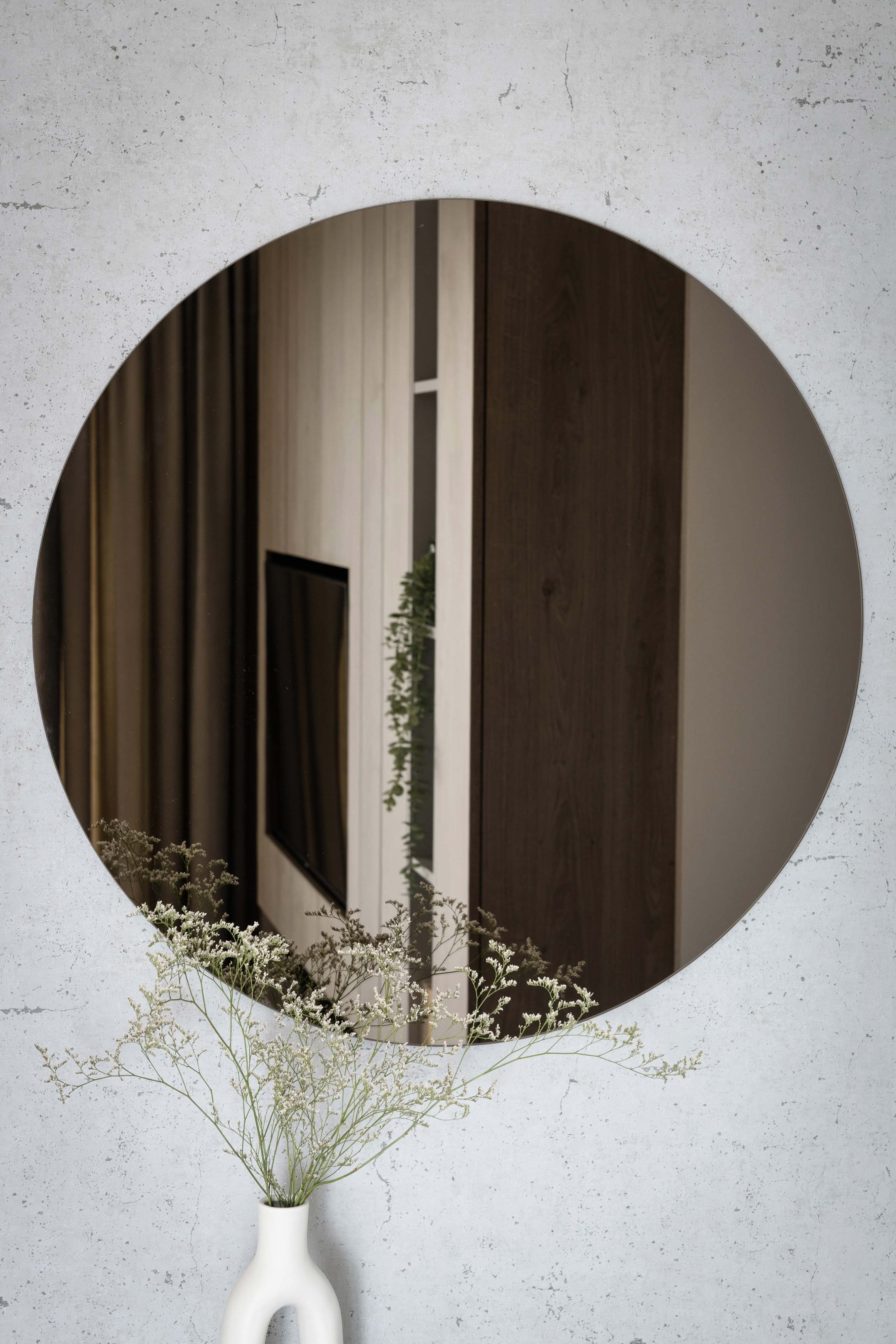 Round mirror with a beveled edge reflecting home dÚcor, featuring custom glass design, perfect for enhancing interior aesthetics.