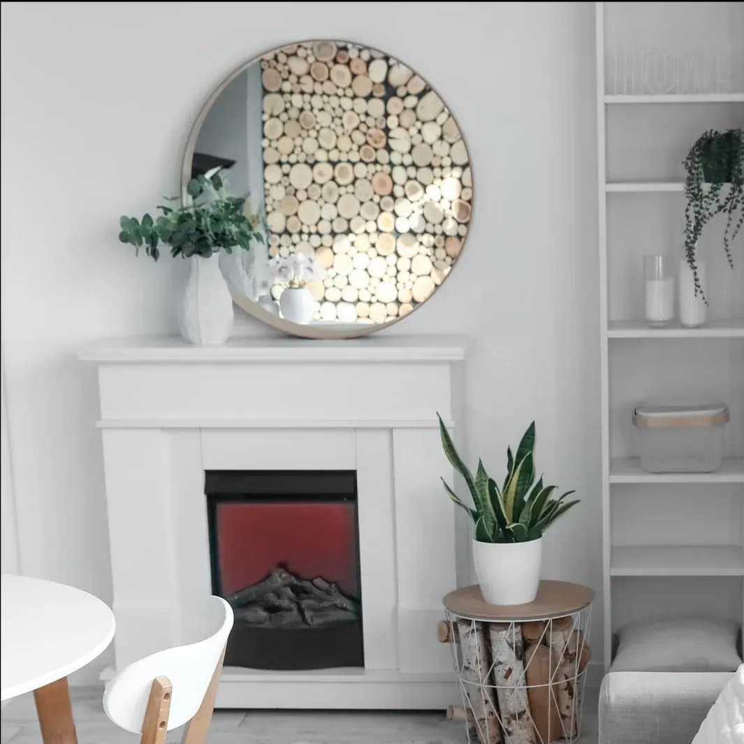 Round beveled glass mirror above a white mantel with decorative elements, showcasing custom glass design in a modern home setting.