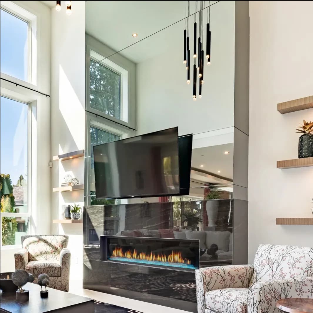 Custom glass mirror reflecting modern living space with TV and fireplace, showcasing elegant design elements and natural light.