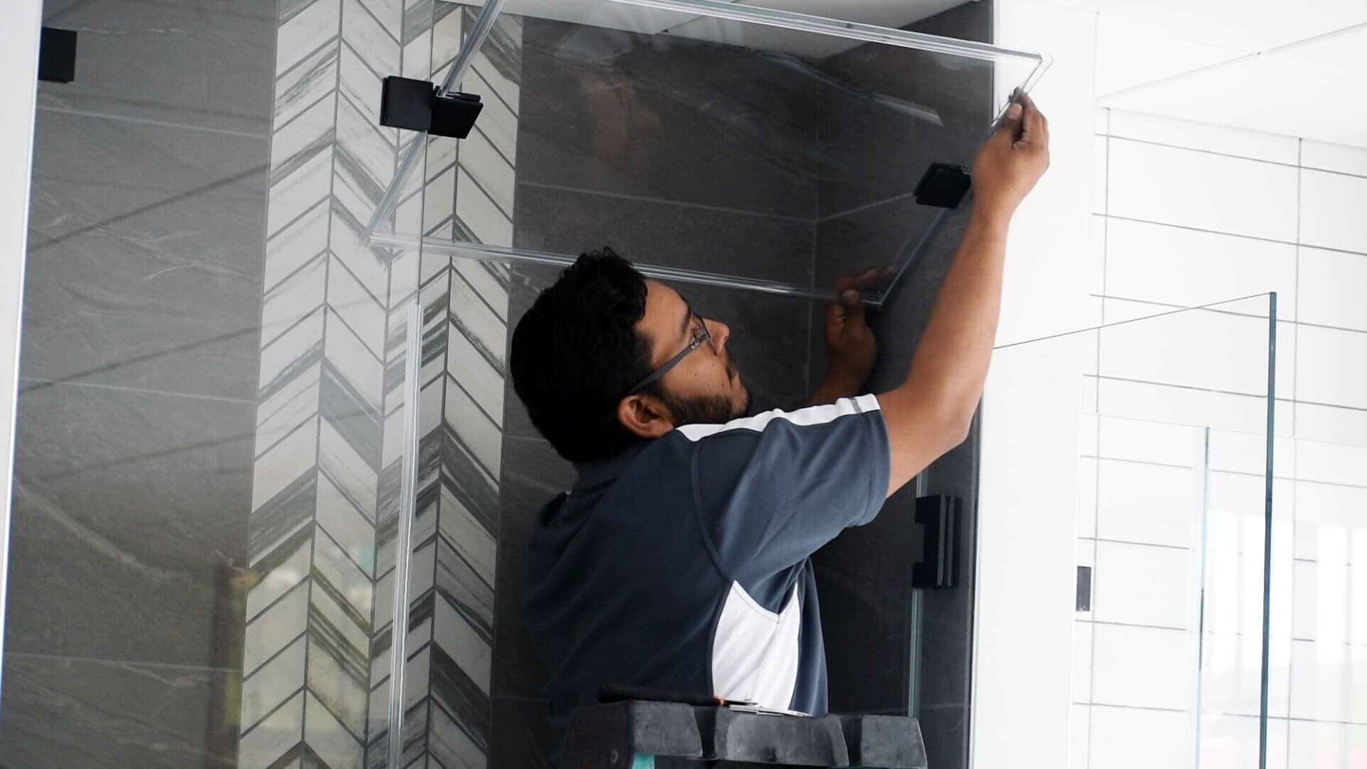 Worker installing custom shower doors with tempered glass, showcasing expertise in glass installation for bathroom upgrades.