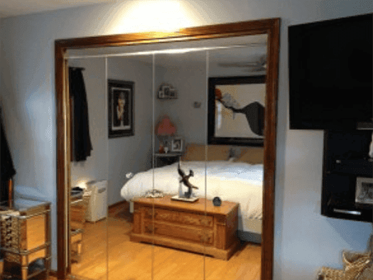Custom glass sliding shower doors with a beveled glass edge in a modern bedroom setting