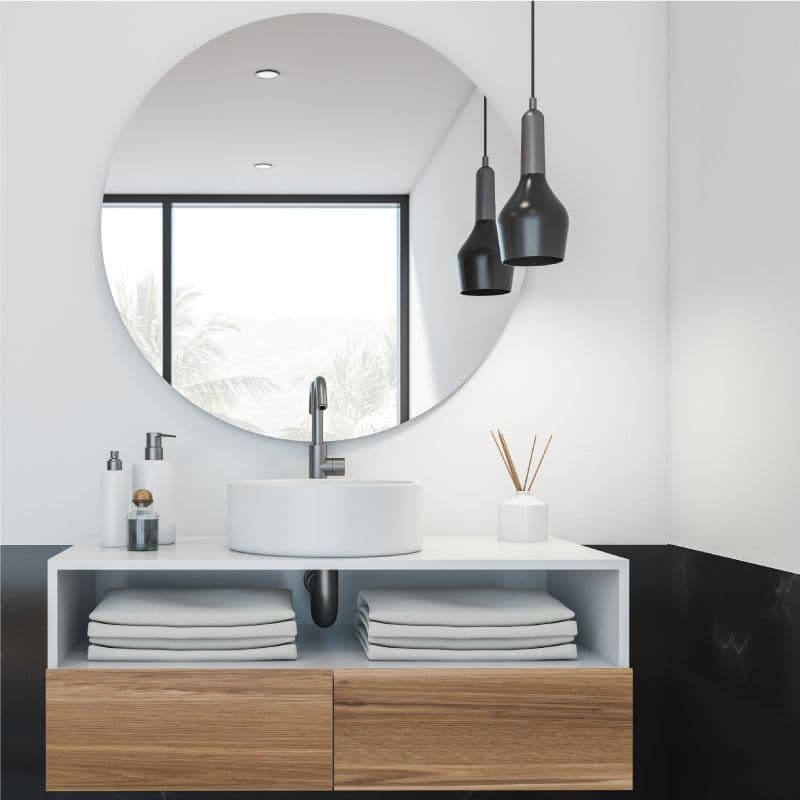 Modern bathroom design featuring a round mirror, sleek countertop basin, and stylish storage; ideal showcase for custom glass solutions like mirrors and shower doors.