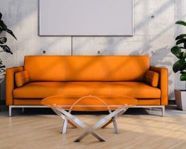 Modern living space featuring an orange sofa and a round glass coffee table with a sleek design, ideal for showcasing custom glass solutions, including tempered and beveled glass edges.