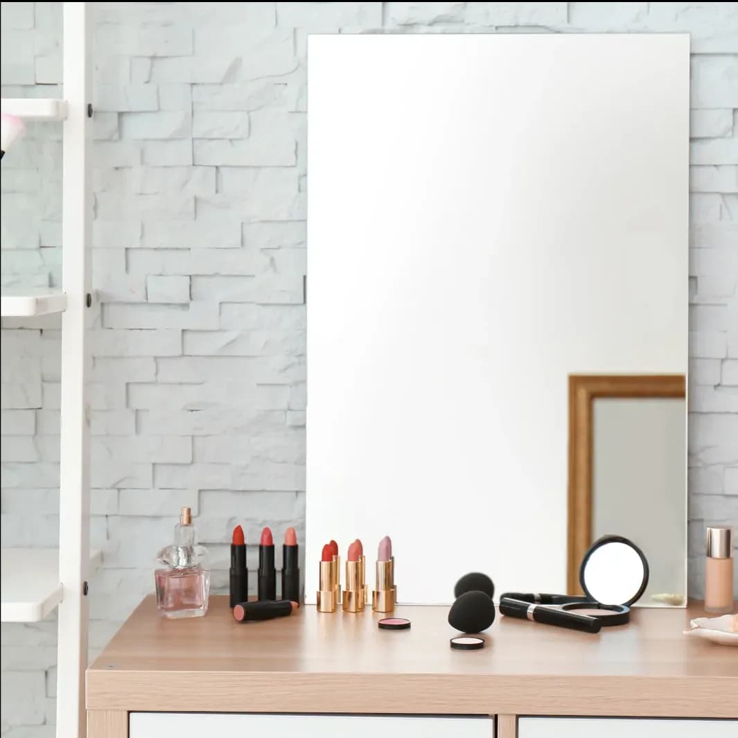Custom glass mirror above a wooden table with makeup products, featuring a chic design that complements shower doors and tempered glass aesthetics.