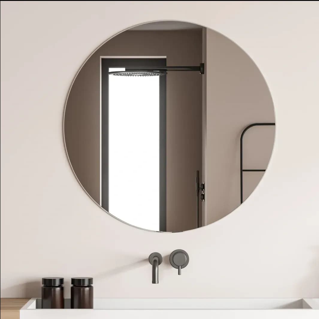 Round mirror reflecting a modern bathroom with shower doors, showcasing custom glass design, complemented by tempered glass and a sleek aesthetic.