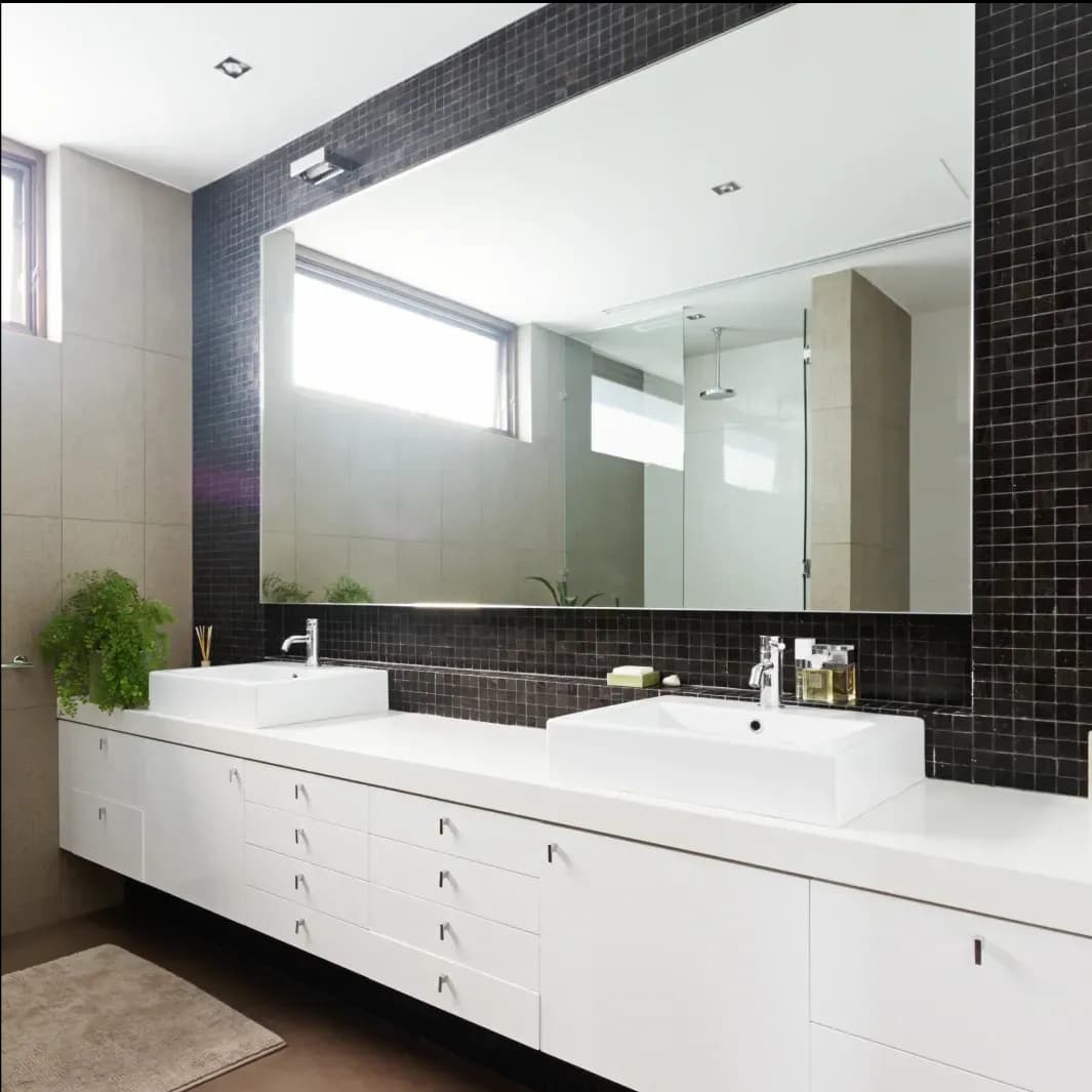Modern bathroom featuring a large custom glass mirror above a sleek vanity with double sinks, showcasing a minimalist design ideal for custom shower doors, tempered glass, and stylish beveled glass edges.