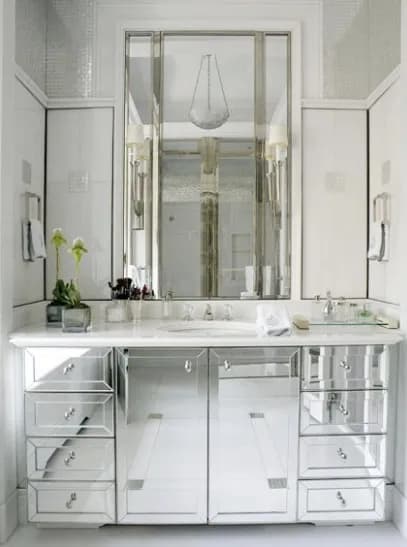 Elegant bathroom featuring custom mirrors and a stylish vanity with mirrored drawer fronts