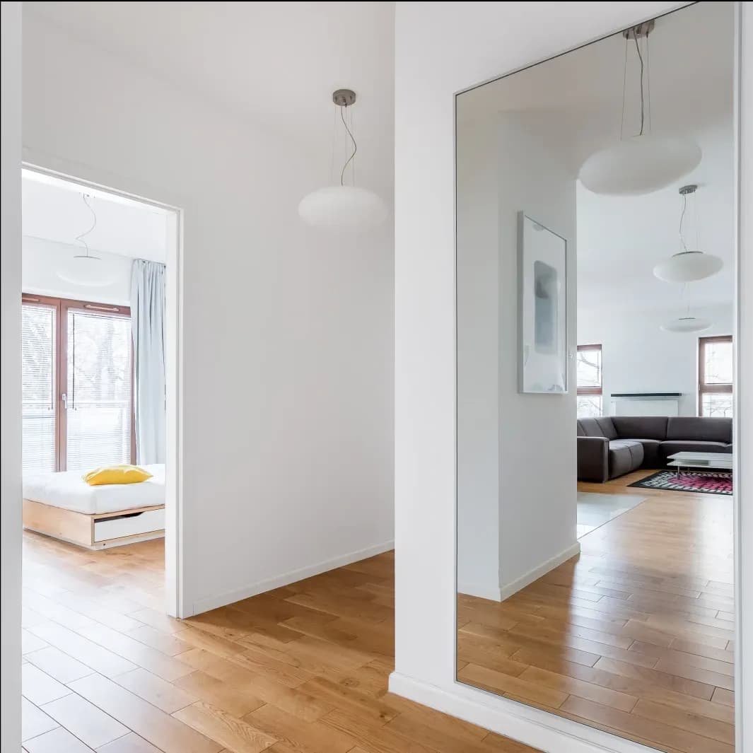 Modern hallway featuring a large custom glass mirror, showcasing sleek design and natural light, ideal for enhancing space and style in homes with custom glass solutions like shower doors and table tops.