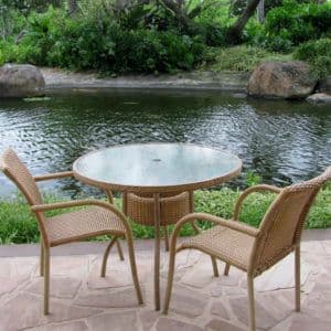 Round glass table with tempered glass top beside a tranquil pond