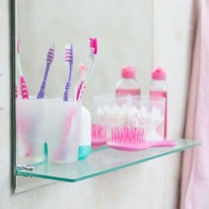 Custom glass shelf supporting toothbrushes and toiletries