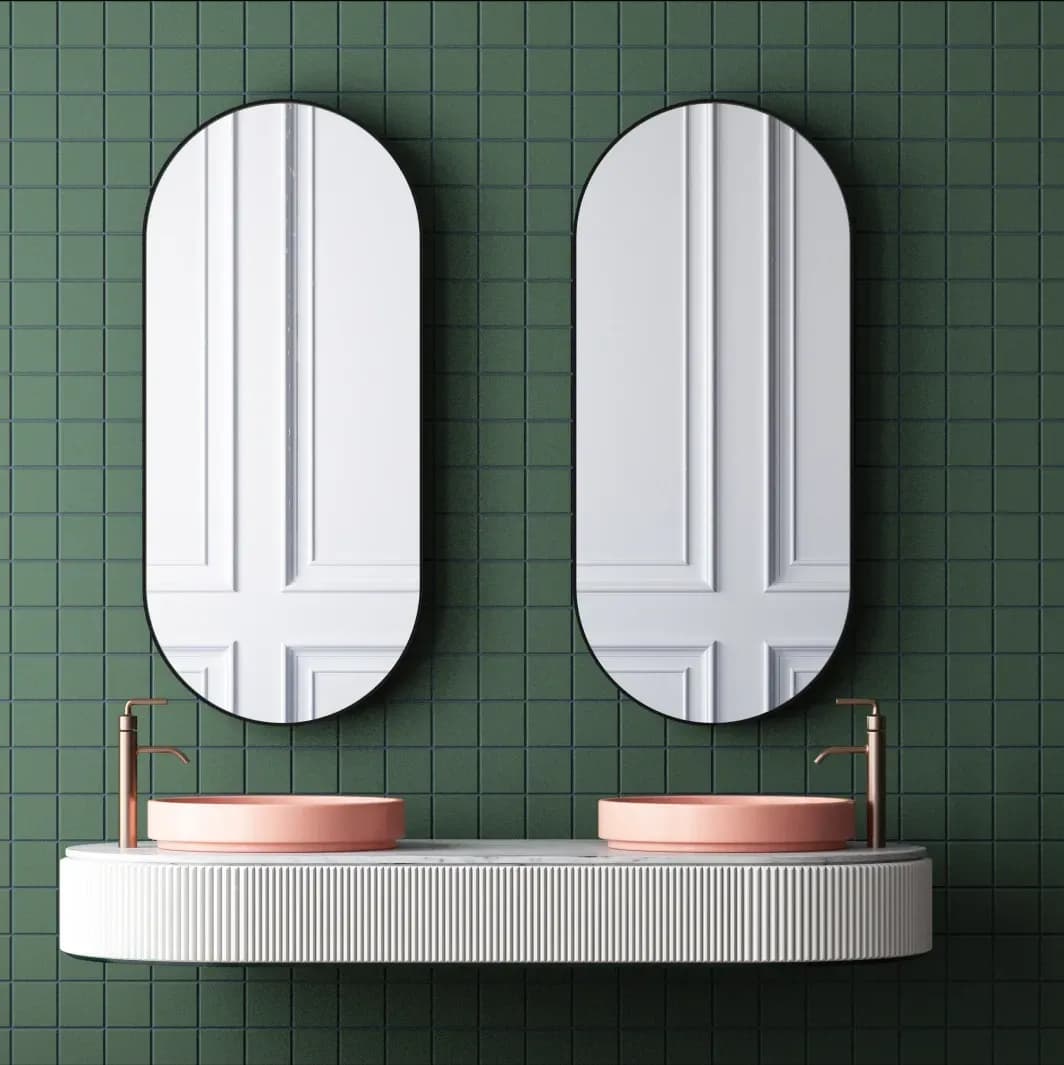 Modern bathroom with custom mirrors, stylish sink tops, and a green tiled background, showcasing quality glass design elements.