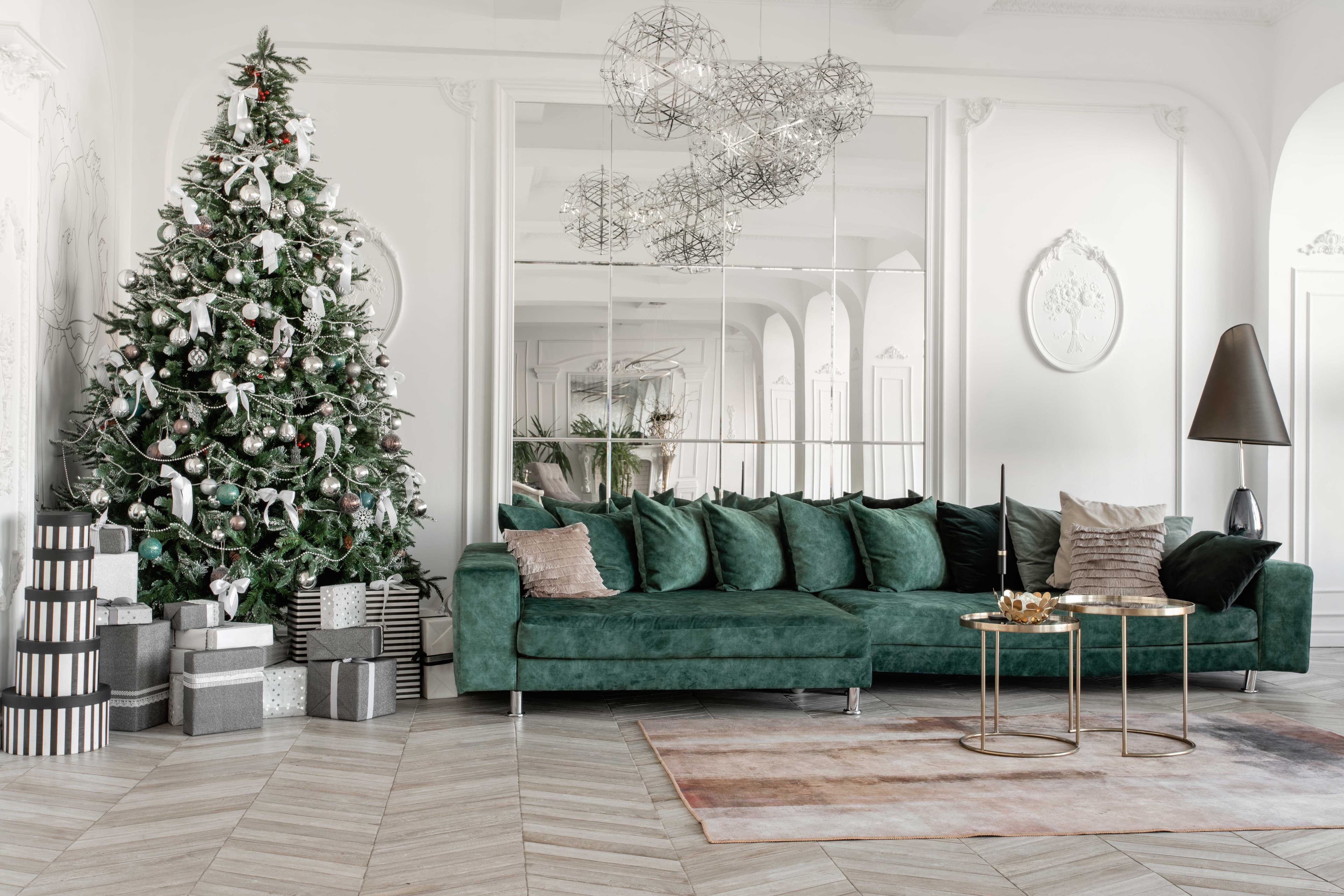 Elegant living room featuring a green sectional sofa, contemporary decor, Christmas tree, and large mirrors reflecting custom glass elements, ideal for showcasing shower doors, table tops, and beveled glass edges.