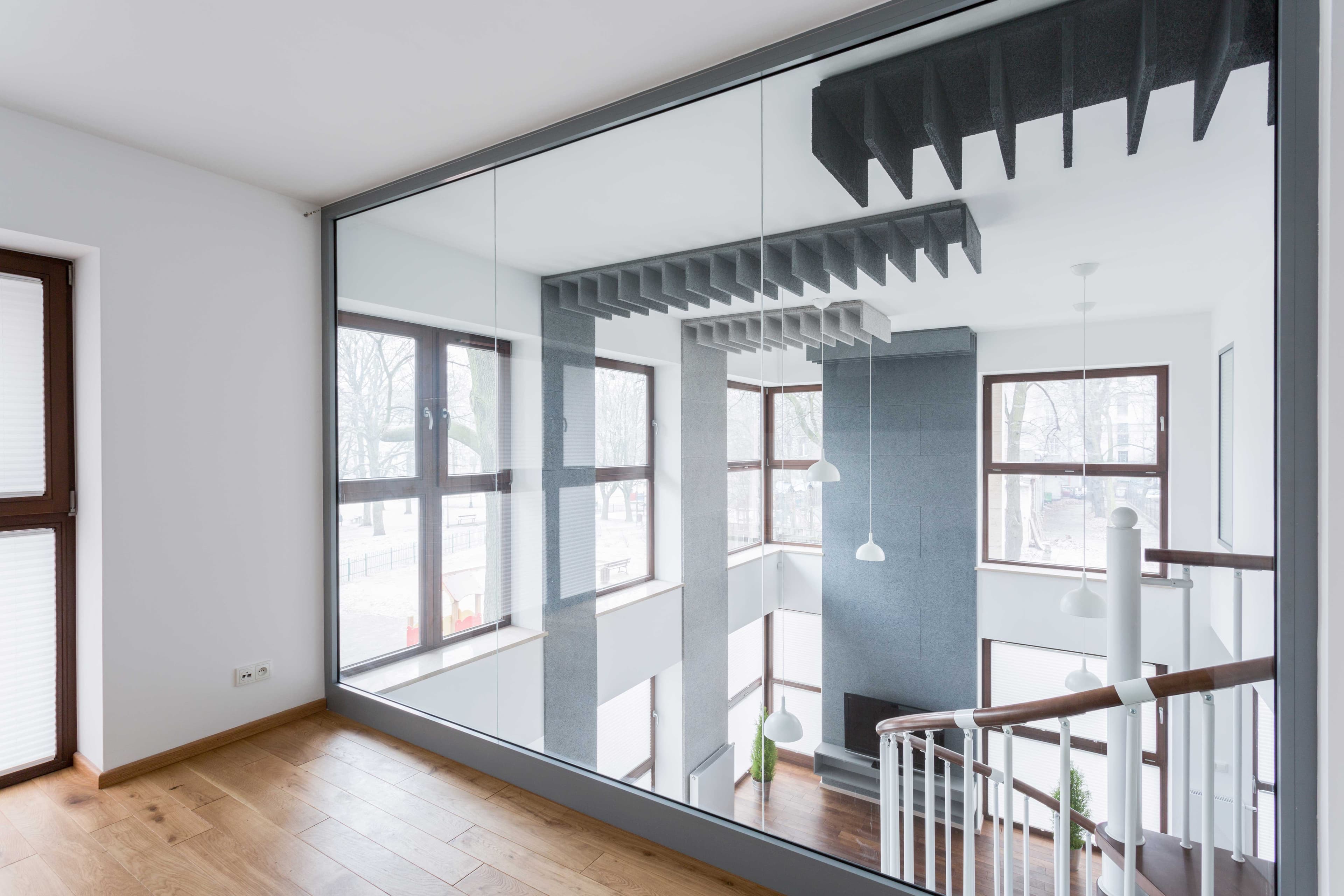 Modern interior with large custom glass wall, featuring tempered and beveled glass edges, enhancing light and space in the staircase area.