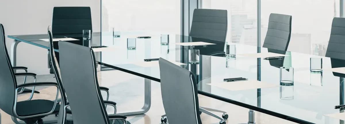 Modern conference room featuring a sleek glass table top, surrounded by stylish chairs, utilizing custom glass solutions ideal for professional spaces.