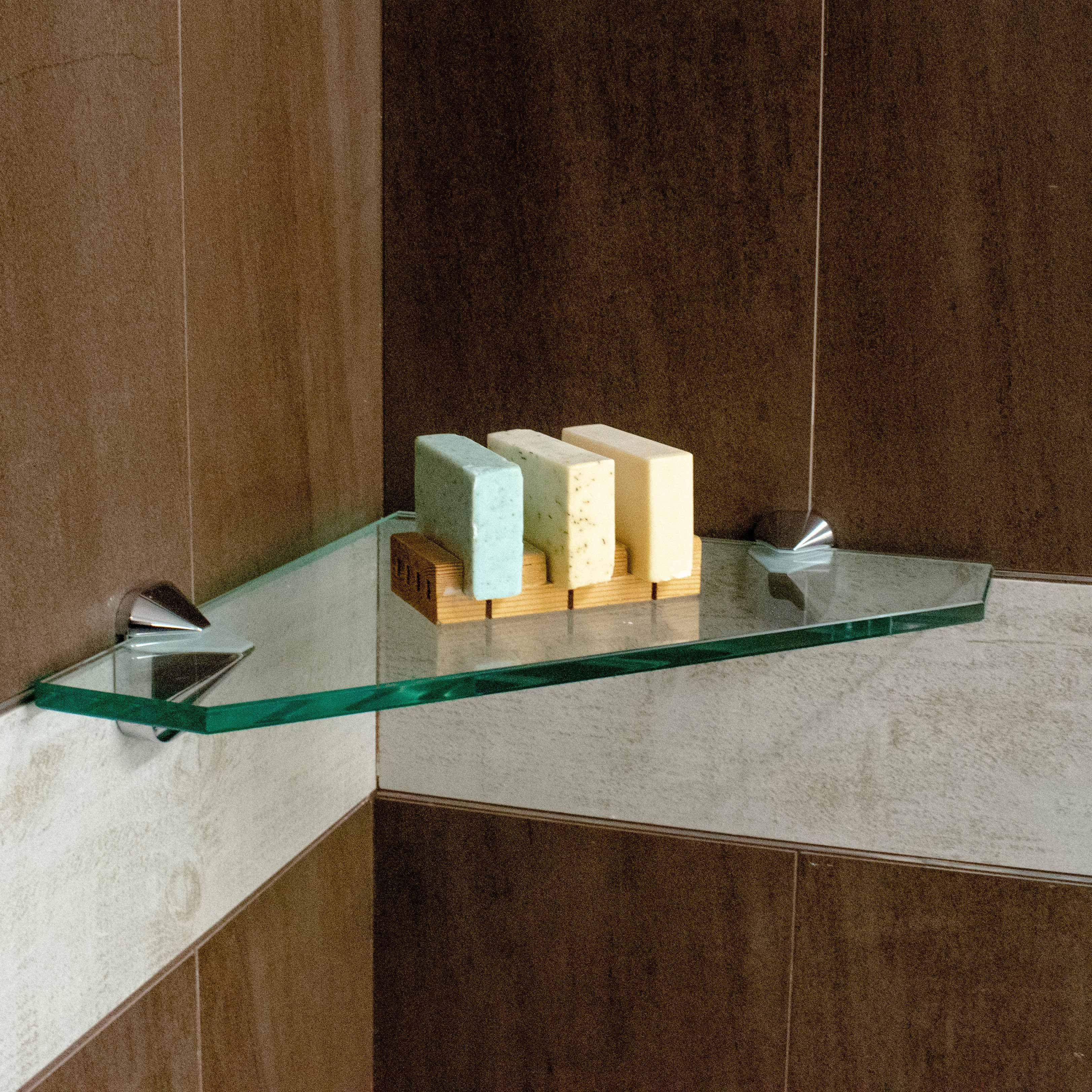 Tempered glass shelf with beveled edges displaying colorful soap bars, ideal for bathroom decor, custom glass solutions, and luxury shower doors.