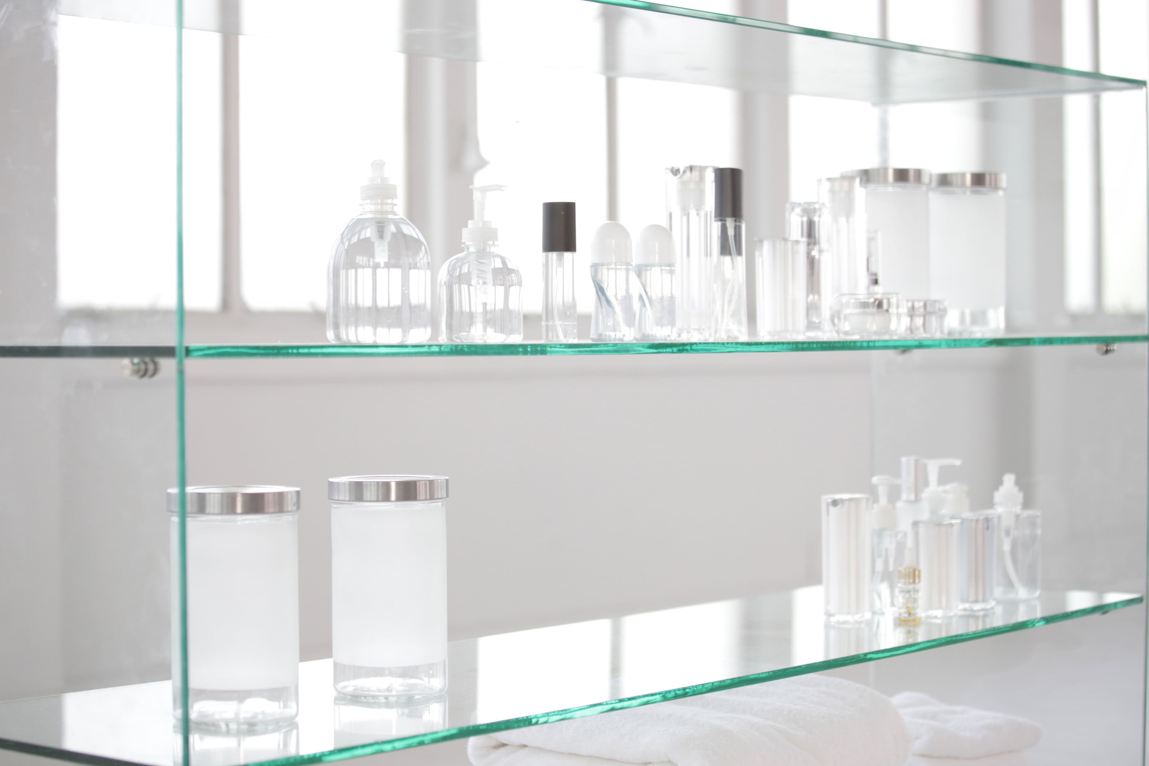 Custom glass shelving displaying various clear containers, perfect for showcasing products alongside shower doors, mirrors, and tempered glass features, with a modern aesthetic.