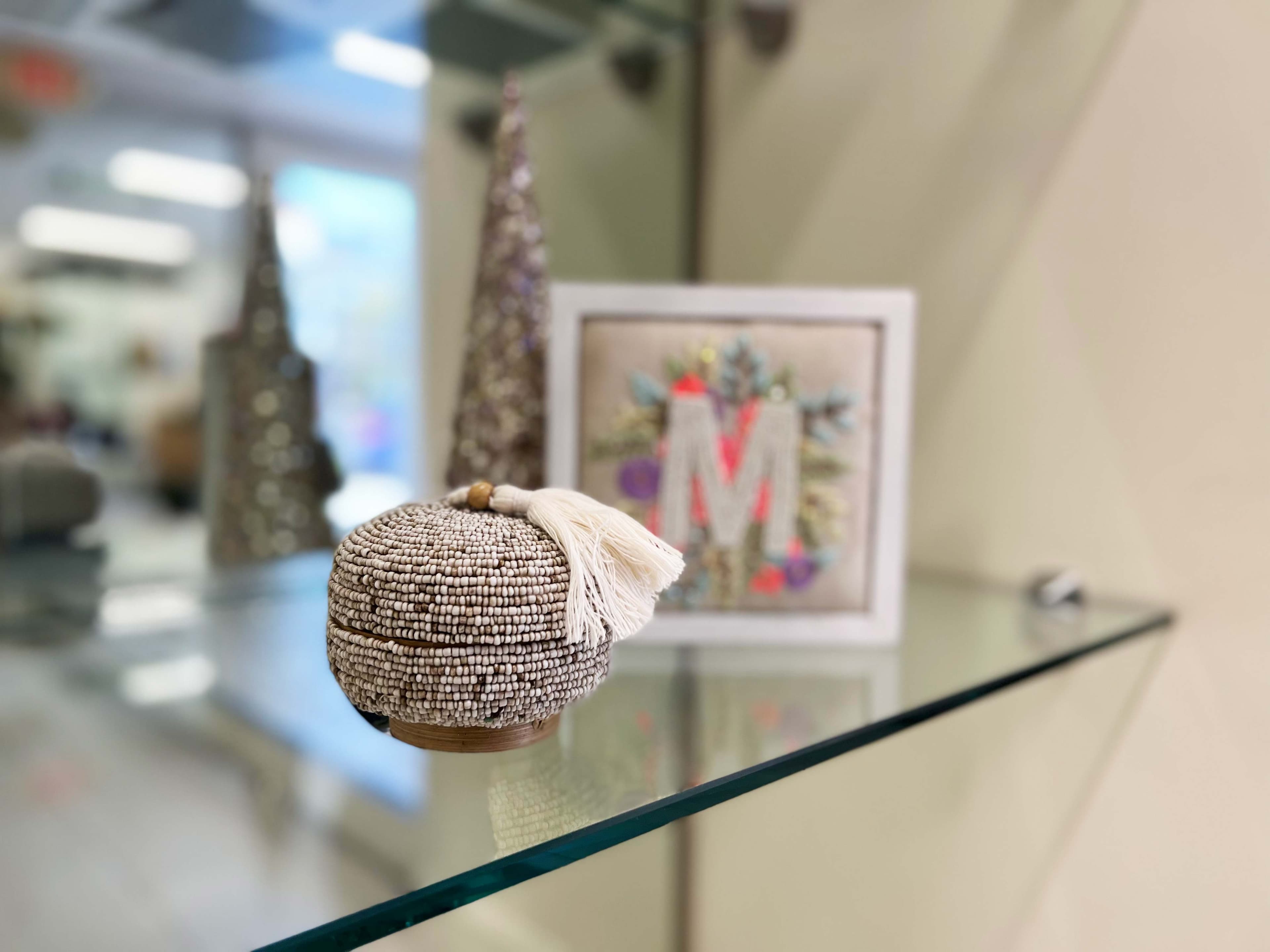Decorative storage on a custom glass table top with beveled edges, showcasing a unique woven container and art piece, highlighting the elegance of tempered glass design.