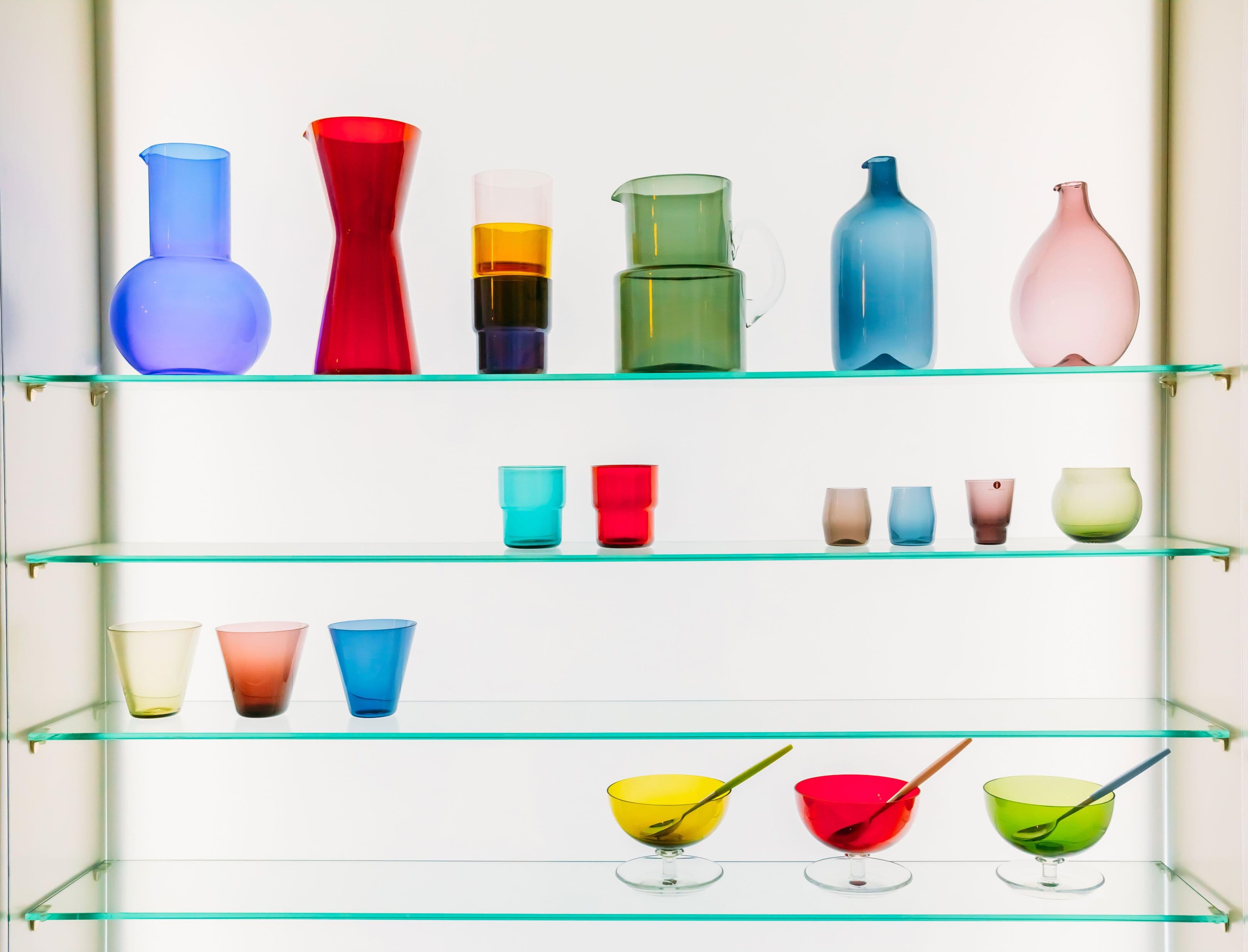 Colorful glass vases and bowls displayed on custom glass shelves, highlighting tempered glass design and beveled glass edges.
