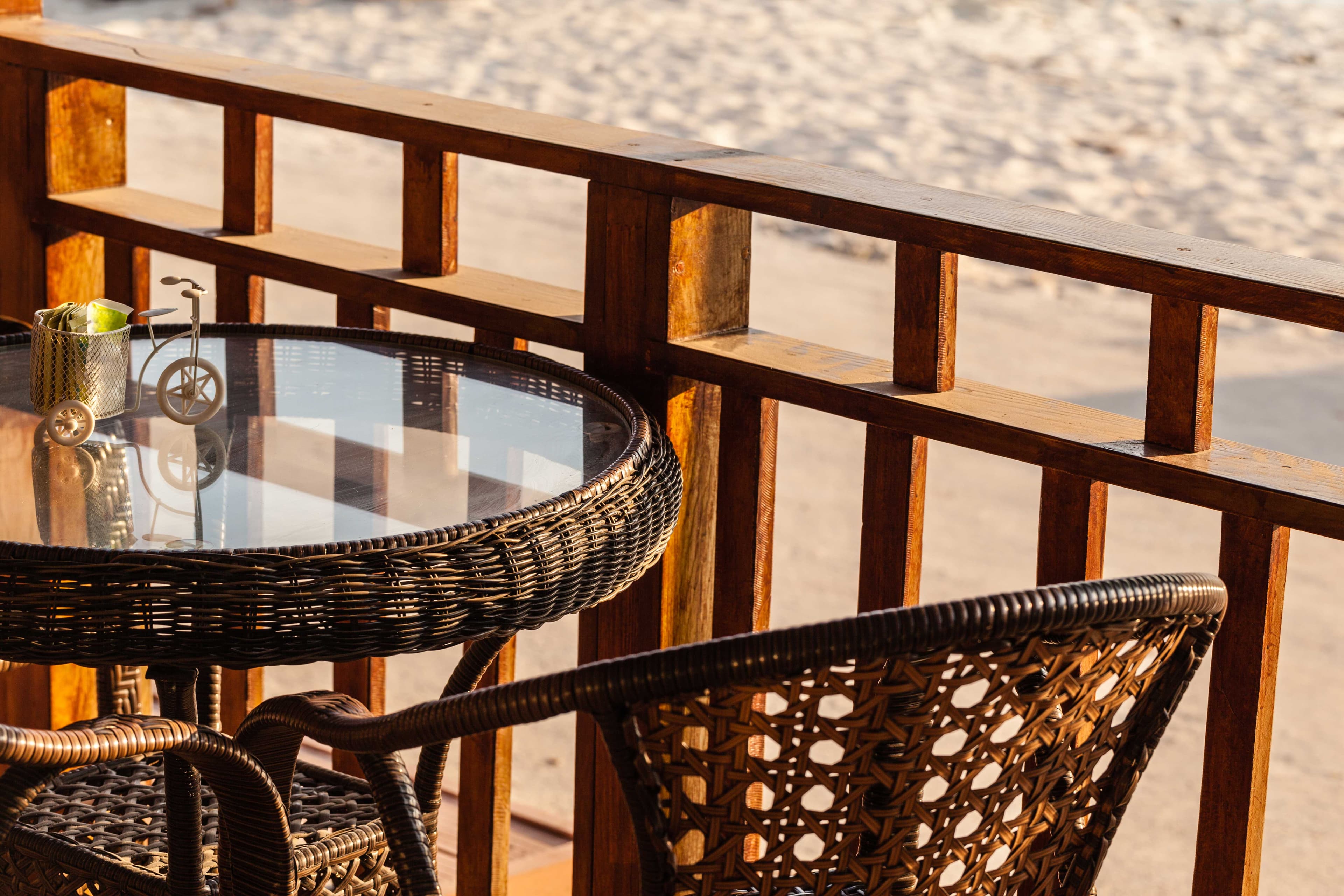 Round glass tabletop on a wicker patio table, showcasing custom glass design with sunlight reflecting off the tempered surface.