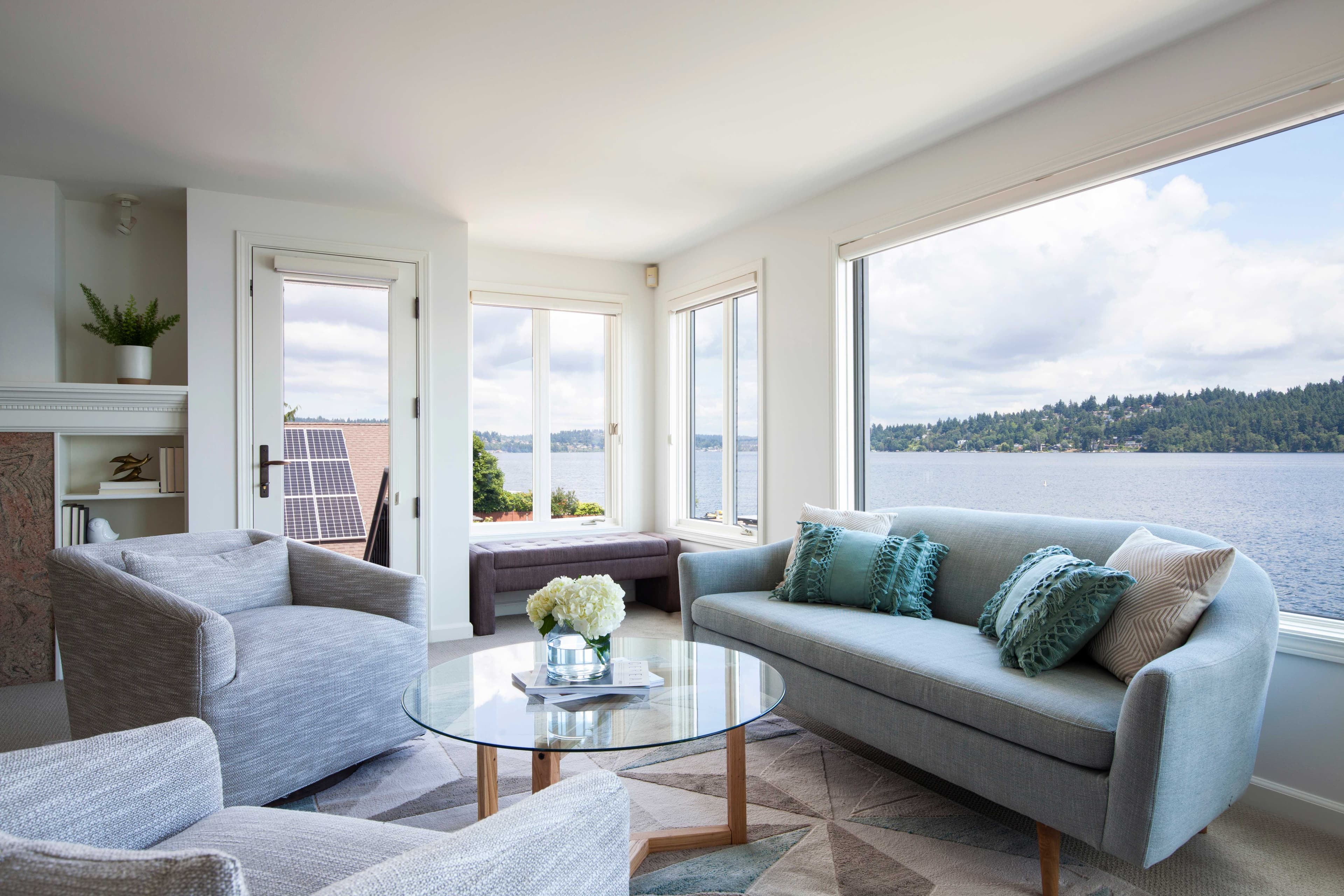 Modern living room featuring a round glass table with a clear tempered glass top, stylish seating, and panoramic views of the waterfront, ideal for showcasing custom glass designs.