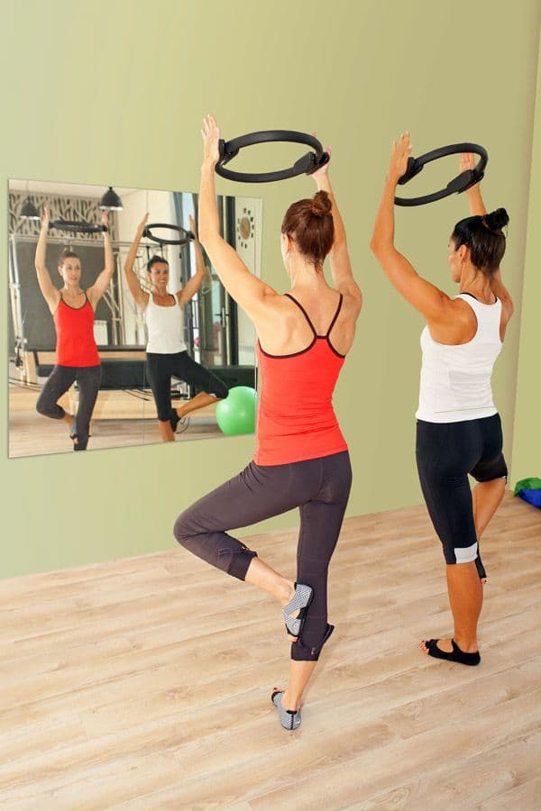 Women performing fitness routines in front of a large wall mirror